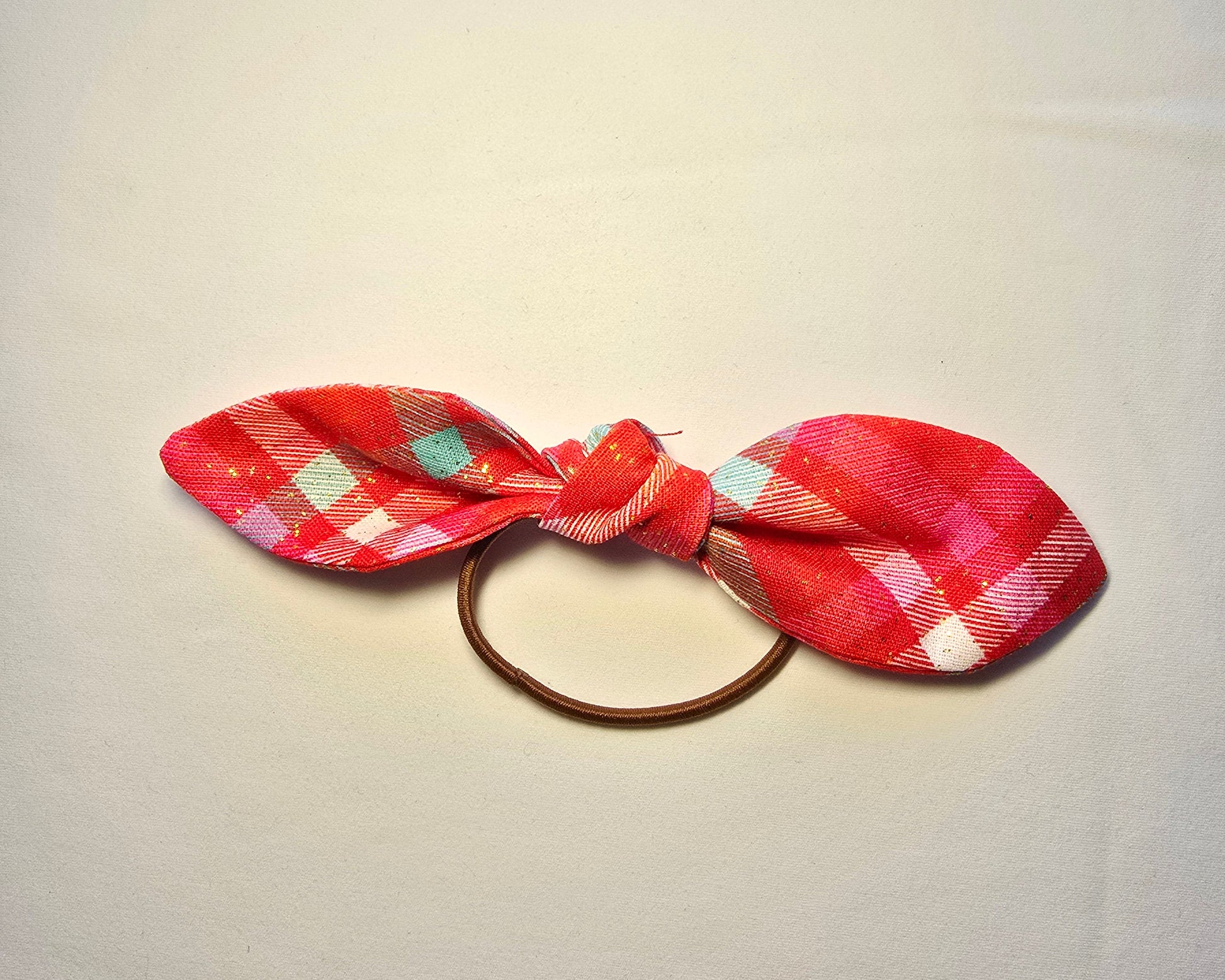 Red plaid bow hair tie on a light gray background